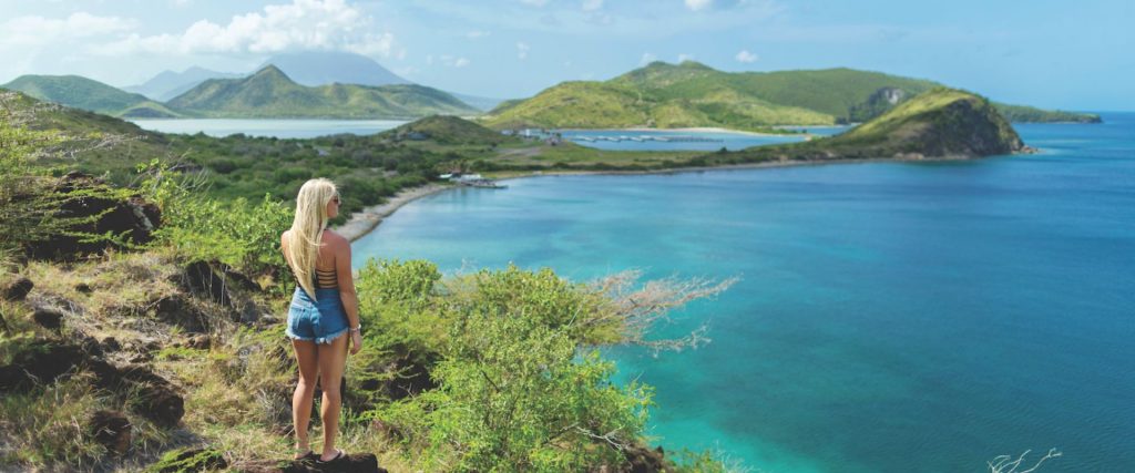 Mujer caminando por una playa de arena blanca rodeada de aguas cristalinas en el Caribe.