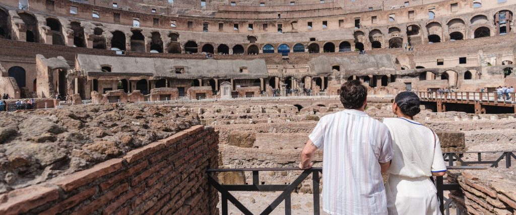 Pareja explorando el Coliseo romano en un día soleado.