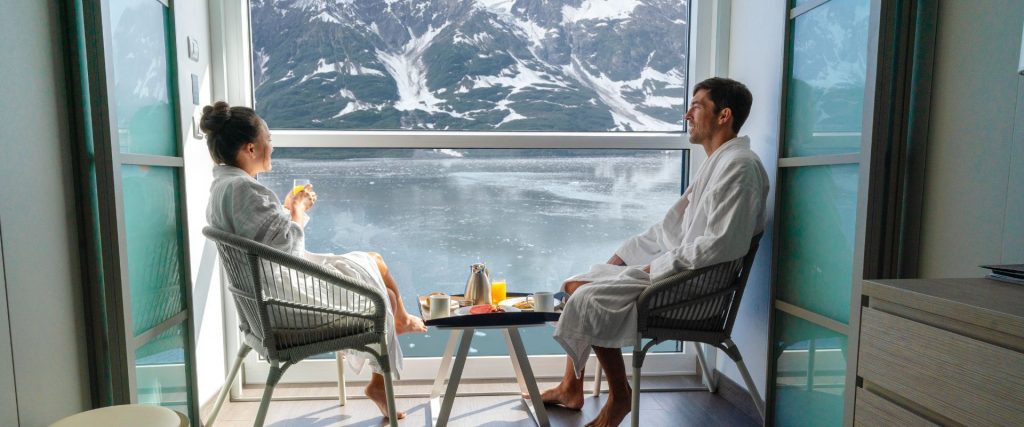 Pareja disfrutando de un desayuno en el balcón privado de su camarote con vistas al mar.